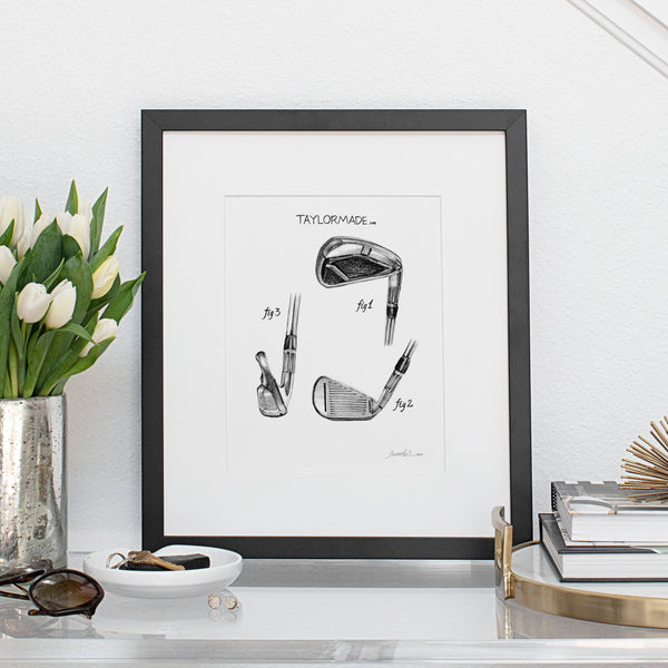 black and white pencil drawing print of Taylormade M4 golf club in a black frame on a table with flowers in a vase