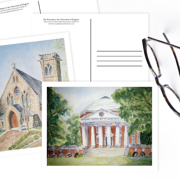 Watercolor postcards of University of Virginia's Rotunda and Chapel on white table.