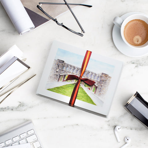 VT Torgersen Bridge notecards tied with maroon and orange ribbon on a modern desk with keyboard, glasses, and latte.