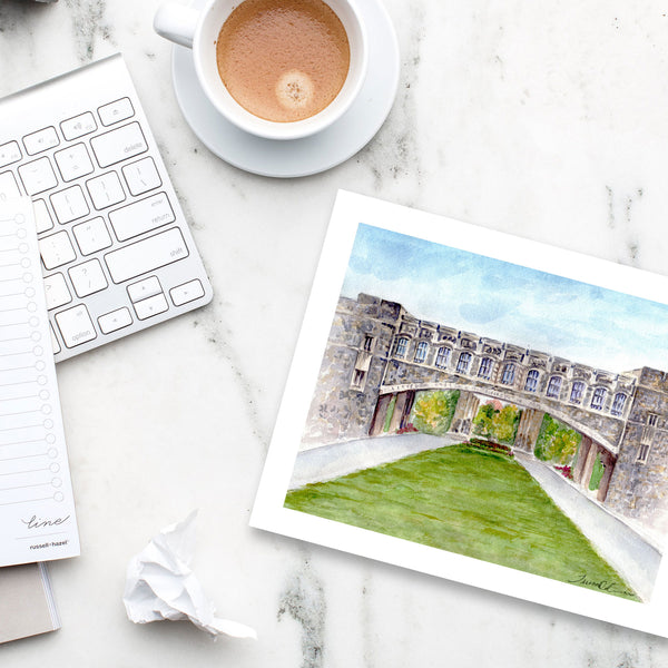 Art print of Virginia Tech Torgersen Bridge notecard on marble desk with latte, keyboard, and stylish office accessories.