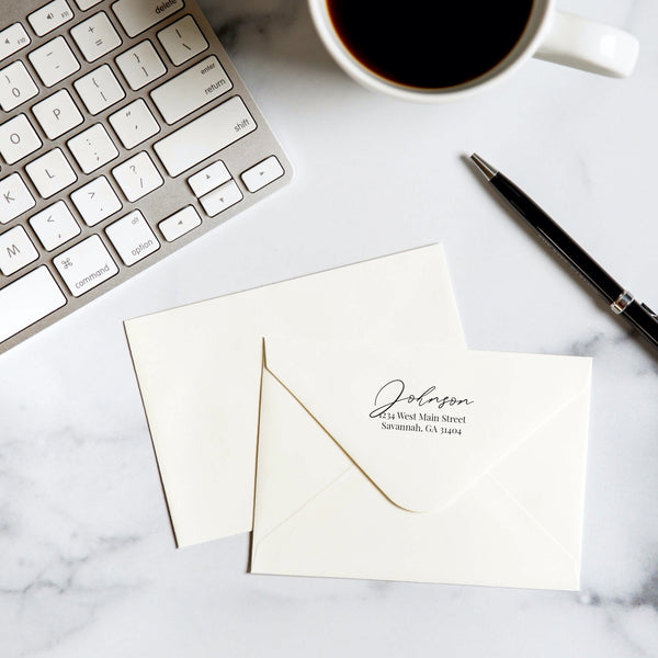 white envelope with keyboard, pen and coffee with script return address